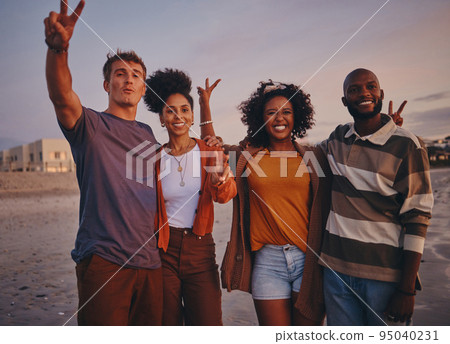Diversity, friends and on beach at sunset show peace, sign or relax together on holiday and vacation. Happy group, smile or on seaside getaway, trip or weekend break have fun, good time or travelling 95040231