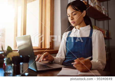 Coffee shop, laptop and finance with a woman manager or small business owner managing the books of her cafe. Startup, entrepreneur and management with a female working online in her restaurant 95040649