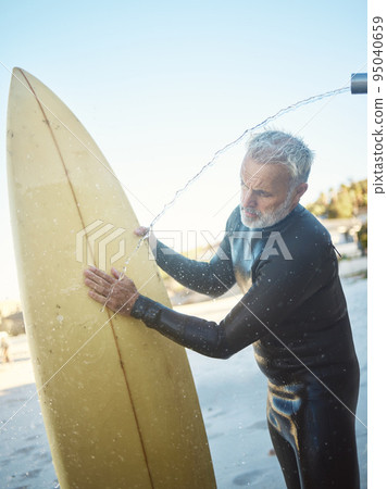Old man, beach and surfer cleaning surfboard, surfing in Mexico on summer holiday or vacation. Washing, shower and elderly retired male remove sand on board after surf or training exercise in ocean. 95040659