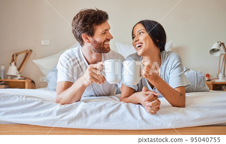 Happy morning, coffee and couple smile in bed feeling relax, love and happiness in a bedroom home. Smiling boyfriend and girlfriend together in a house laughing and spending quality time drinking tea 95040755