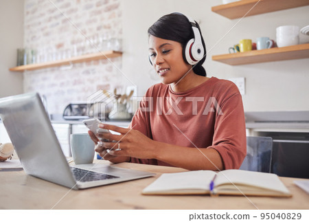 Social media, music and business woman typing an email on a mobile app on phone working on laptop in house. Remote entrepreneur or worker reading on the internet, listening to radio and planning work 95040829