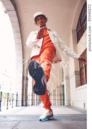 Fashion, model and gen z man from Spain with neon, trendy and luxury brand clothes. Clothing brand and leg kick pose of a hipster Spanish person with sports shoes posing by a building outdoors Fashion, model and gen z man from Spain with neon, trendy and luxury brand clothes. Clothing brand and leg kick pose of a hipster Spanish person with sports shoes posing by a building outdoors 95040872