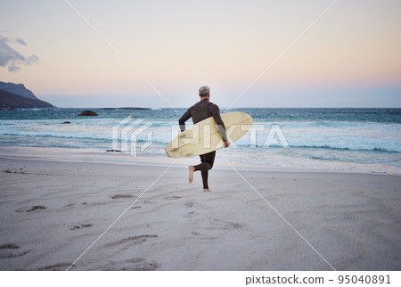 Surf at the beach, man and running to ocean with surfboard for the waves, fitness and adventure. Mature surfer at sunrise, in wet suit and to enjoy the sea, travel and summer on an island. Surf at the beach, man and running to ocean with surfboard for the waves, fitness and adventure. Mature surfer at sunrise, in wet suit and to enjoy the sea, travel and summer on an island. 95040891