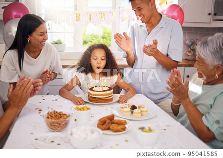 Birthday, children and cake with a girl in celebration with family at a party while blowing out her candles to make a wish. Kids, applause and happy with a daughter, parents and grandparents at home 95041585