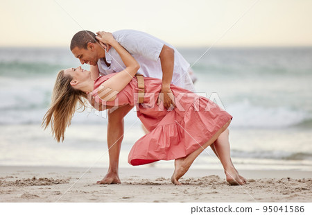 Love, dance and couple dancing at the beach in summer celebrate their marriage, happiness and honeymoon vacation. Smile, sunset and happy woman celebrating a healthy relationship with partner at sea 95041586