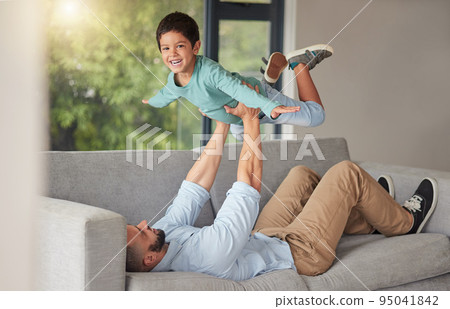 Happy family, love and father and son bonding on a sofa at home, playing and being creative with a fun game. Energy, fantasy and airplane pose by happy boy enjoying free time with his caring dad 95041842