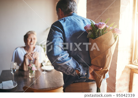 Surprise, flowers and senior couple in celebration of an anniversary, marriage or birthday at a restaurant. Elderly man giving bouquet of roses to woman during dinner date for love at a coffee shop Surprise, flowers and senior couple in celebration of an anniversary, marriage or birthday at a restaurant. Elderly man giving bouquet of roses to woman during dinner date for love at a coffee shop 95042339