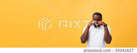 Young Stressed man with hand on his face showing sadness and despair. Isolated over yellow background. 95042627