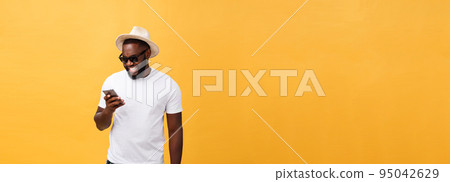 Cheerful African American man in white shirt using mobile phone application. happy dark skinned hipster guy read news from social network in mobile phone. 95042629