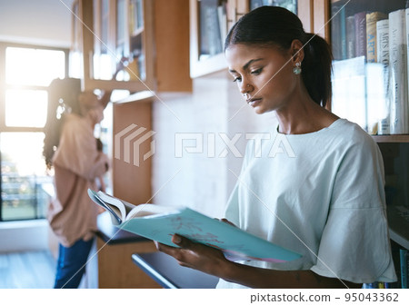 Woman, student and reading a book in library for education, learning and knowledge indoors. Focused female doing research for school project at university in study with books for information Woman, student and reading a book in library for education, learning and knowledge indoors. Focused female doing research for school project at university in study with books for information 95043362