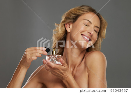 Mature woman, spraying beauty perfume scent and smiling in gray studio background mockup. Bottle of fragrance spray for happy women, self care wellness and luxury cosmetic product for body wellbeing Mature woman, spraying beauty perfume scent and smiling in gray studio background mockup. Bottle of fragrance spray for happy women, self care wellness and luxury cosmetic product for body wellbeing 95043467