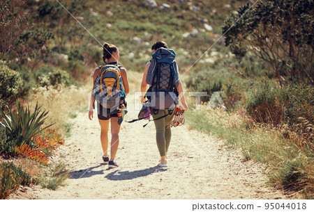 Fitness and workout friends hiking or walking in nature on a mountain dust path. Women and guide on a walk in remote environment with rough terrain with freedom, backpack and journey outdoor trekking Fitness and workout friends hiking or walking in nature on a mountain dust path. Women and guide on a walk in remote environment with rough terrain with freedom, backpack and journey outdoor trekking 95044018