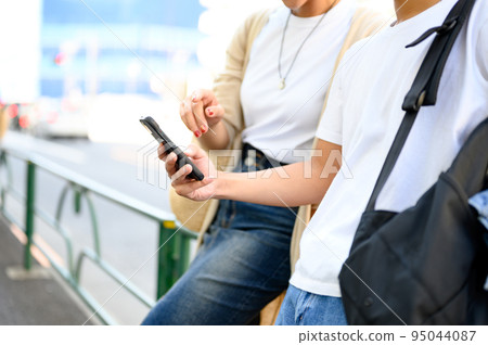 Men and women looking at smartphones, couples, research Men and women looking at smartphones, couples, research 95044087