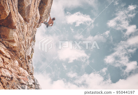 Rock climbing, sports and adventure with man on mountain against a blue sky background for fitness, challenge and training. Motivation, freedom and strong male athlete on cliff for adrenaline Rock climbing, sports and adventure with man on mountain against a blue sky background for fitness, challenge and training. Motivation, freedom and strong male athlete on cliff for adrenaline 95044197