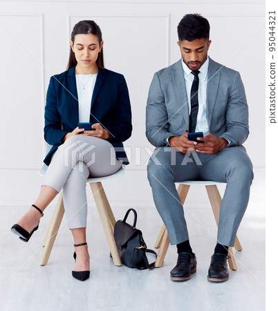 Hiring, interview and phone of businessman and woman with diversity in a office waiting room. Corporate potential workers wait for a company human resources meeting with technology and 5g internet Hiring, interview and phone of businessman and woman with diversity in a office waiting room. Corporate potential workers wait for a company human resources meeting with technology and 5g internet 95044321