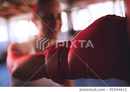 Boxing, fitness and sport with strong woman, boxing gloves to hit, punch and fight during training at a gym. Fit and athletic boxer female doing a workout during self defense exercise class Boxing, fitness and sport with strong woman, boxing gloves to hit, punch and fight during training at a gym. Fit and athletic boxer female doing a workout during self defense exercise class 95044612