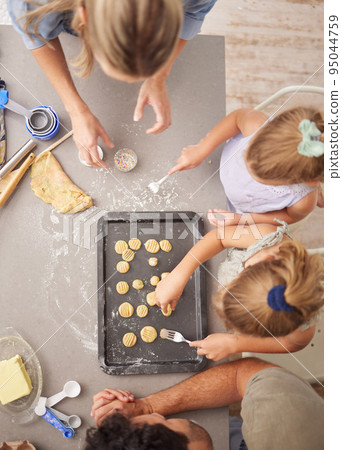 Baking, family and girl children learning to bake cookies in kitchen at home from above with mom, dad and sister. Man, woman and kids having fun with dough, cooking and food together making pastry 95044759