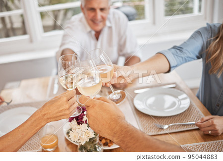 Family, wine and toast in celebration of of a holiday or good news at table, happy and cheerful in their home. Relax, smiling and excited people cheers before lunch, hungry and ready to share a meal 95044883