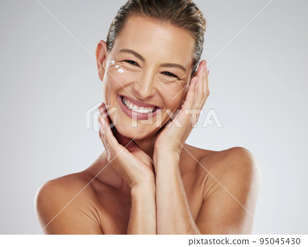 Model, cream and skincare with hands on mature face in beauty, wellness and happiness with smile in portrait. Woman, skin and happy for dermatology, cosmetic and health against studio background Model, cream and skincare with hands on mature face in beauty, wellness and happiness with smile in portrait. Woman, skin and happy for dermatology, cosmetic and health against studio background 95045430