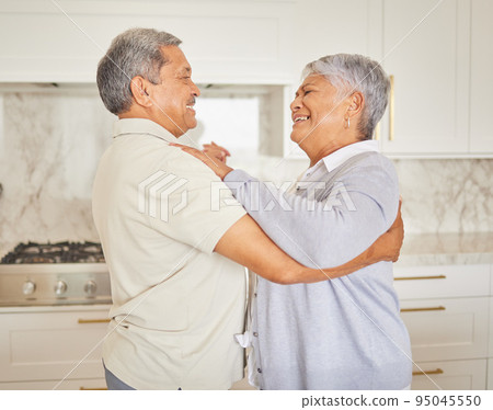 Love, happy and elderly couple dance in a kitchen at home, bonding and having fun. Mature man and woman hug, being playful and loving, enjoying their relationship and retirement together indoors 95045550