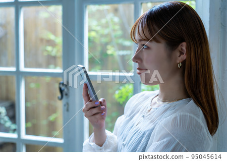 在窗邊使用智能手機的年輕女子 95045614