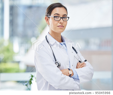 Portrait of a doctor with arms crossed in her consultation office with glasses and a stethoscope. Woman healthcare professional standing in a room in a medicare hospital, clinic or surgery center. Portrait of a doctor with arms crossed in her consultation office with glasses and a stethoscope. Woman healthcare professional standing in a room in a medicare hospital, clinic or surgery center. 95045998