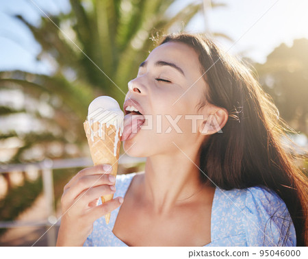 Ice cream cone eating, woman and summer dessert to enjoy on vacation, holiday and relaxing weekend in Portugal. Happy young girl licking melting gelato icecream outdoors for cool, fun and sweet snack 95046000