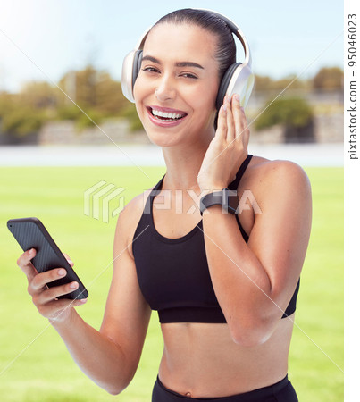 Headphones, fitness and smartphone with woman listening to motivation podcast or music outdoor on sports field with portrait. Athlete girl with 5g cellphone and audio for workout training or exercise Headphones, fitness and smartphone with woman listening to motivation podcast or music outdoor on sports field with portrait. Athlete girl with 5g cellphone and audio for workout training or exercise 95046023