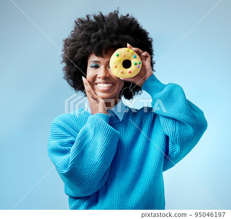 Black woman, smile and donut with blue makeup against studio background. Model, happy and beauty with cake in hand by face show happiness against fashion backdrop with hair, skin and healthy teeth Black woman, smile and donut with blue makeup against studio background. Model, happy and beauty with cake in hand by face show happiness against fashion backdrop with hair, skin and healthy teeth 95046197