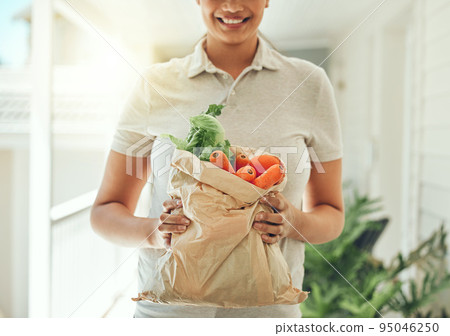 Healthy food, delivery and vegetables in brown grocery paper bag for clean vegan diet with fresh organic ingredients in hands of woman standing at home. Nutrition, vegetarian and health of a female Healthy food, delivery and vegetables in brown grocery paper bag for clean vegan diet with fresh organic ingredients in hands of woman standing at home. Nutrition, vegetarian and health of a female 95046250