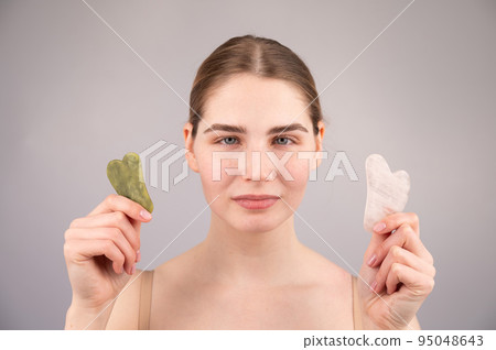 Close-up portrait of a woman holding two gouache scrapers near her face.  95048643