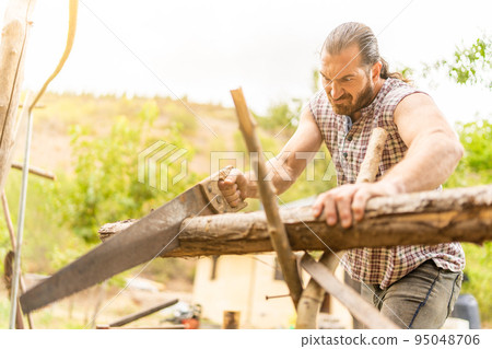 Man making an effort to cut a log 95048706