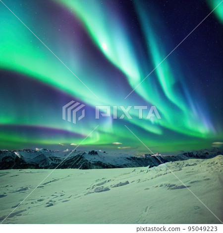 Aurora borealis over snow covered valley in mountain at night 95049223
