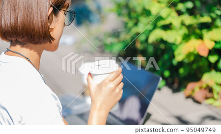 在露台上喝咖啡時看電腦的女人 在露台上喝咖啡時看電腦的女人 95049749
