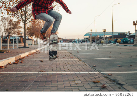 Skateboarding. A man does an Ollie stunt on a skateboard. Jump in the air. Close-up of legs Skateboarding. A man does an Ollie stunt on a skateboard. Jump in the air. Close-up of legs 95052265