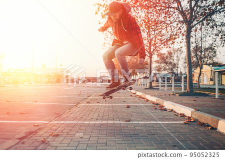 Skateboarding. A man does an Ollie stunt on a skateboard. Jump in the air. Street on the background. Sunlight 95052325