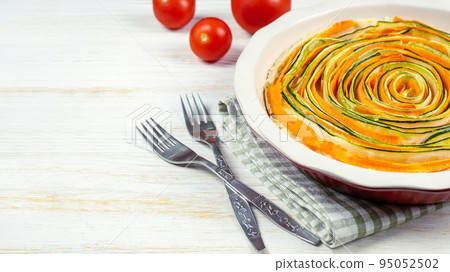 Homemade spiral vegetable tart pie of carrots, zucchini and eggplant on white wooden background Homemade spiral vegetable tart pie of carrots, zucchini and eggplant on white wooden background 95052502