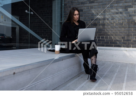 Business woman working on laptop online sitting on steps Business woman working on laptop online sitting on steps 95052658