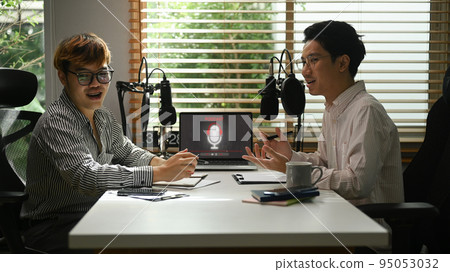 Shot of male radio host discussing various topics with guest during streaming live audio podcast from home studio 95053032