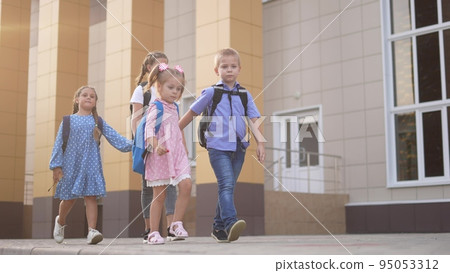 back to school. a group of schoolchildren with backpacks walk next to the school. education kids concept. schoolboy and schoolgirl going to school. lifestyle a group of children walking 95053312