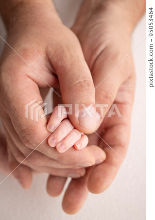 The hand of a sleeping newborn in the hand of parents, mother and father close-up. Tiny fingers of a newborn. The family is holding hands. Studio macro photography. Concepts of family and love. The hand of a sleeping newborn in the hand of parents, mother and father close-up. Tiny fingers of a newborn. The family is holding hands. Studio macro photography. Concepts of family and love. 95053464