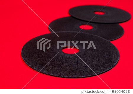 A cut-off wheel for a grinder tool on a red background with a place for copyspace text. Tools for construction and repair, workshop. 95054038