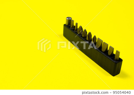 A set of screwdriver nozzles for a screwdriver on a yellow background with space for copyspace text. Tools for construction and repair shop 95054040