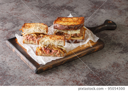 patty melt sandwich has a burger patty covered with melted Swiss cheese, caramelized onions, and griddled slices of rye bread closeup. Horizontal patty melt sandwich has a burger patty covered with melted Swiss cheese, caramelized onions, and griddled slices of rye bread closeup. Horizontal 95054300