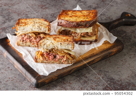 patty melt is a sandwich consisting of a ground beef patty with melted cheese and topped with caramelized onions between two slices of griddled bread closeup 95054302