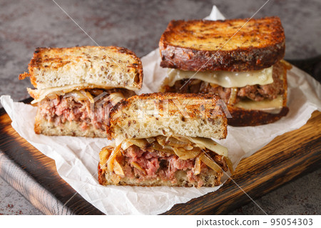patty melt sandwich is a variant of the classic American cheeseburger using crispy bread, cheese, and tender onions closeup on the wooden board. Horizontal 95054303