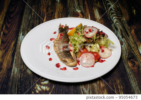 Baked sea fish with vegetables radish, lettuce, lemon and tomatoes. Good proper nutrition, weight loss, maintaining the health of the body. Keto diet, gluten-free diet. 95054673