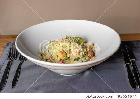 Salad with hard yellow cheese, herbs and chicken meat in a white plate. Restaurant menu 95054674