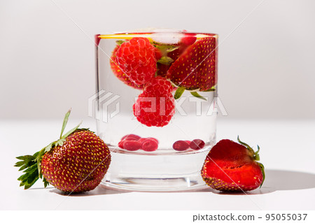 Summer cocktail with strawberries, raspberries and ice on a white background, side view. Summer cocktail with strawberries, raspberries and ice on a white background, side view. 95055037