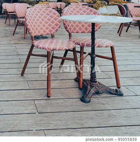 Outdoor table and two chairs near a cafe on a pavement made of tiles. 95055839